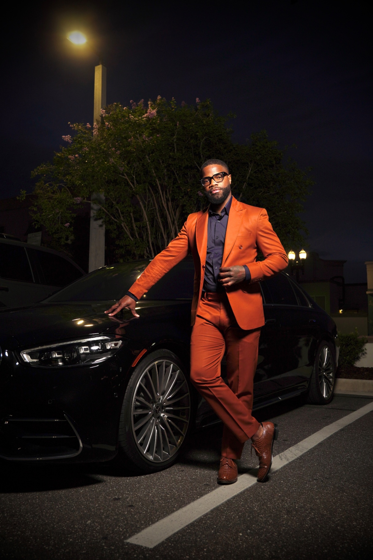 Ricky in a burnt-orange suit at night