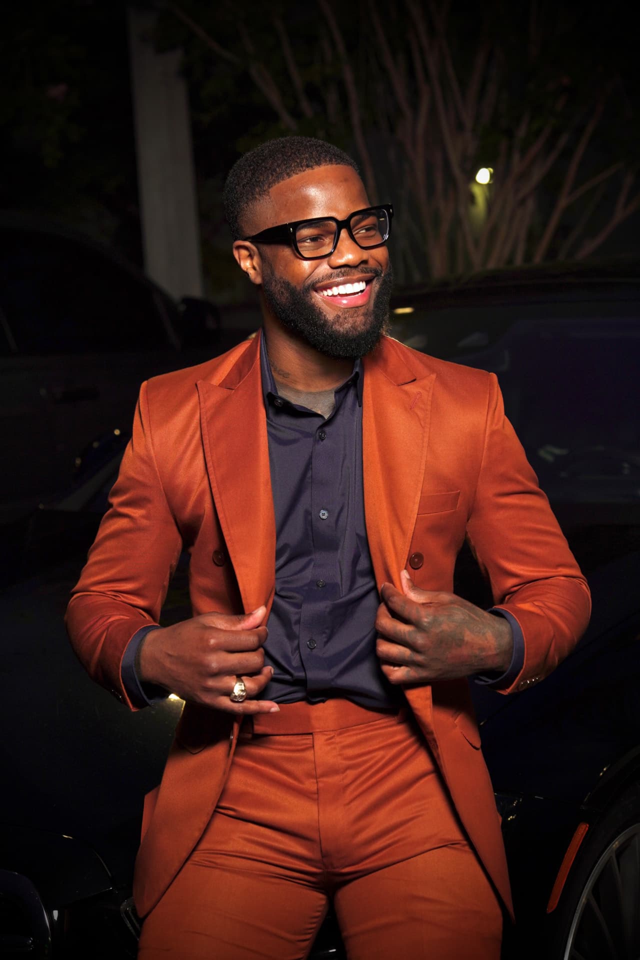 Rickie Edwin in a burnt-orange suit, smiling on the podcast set
